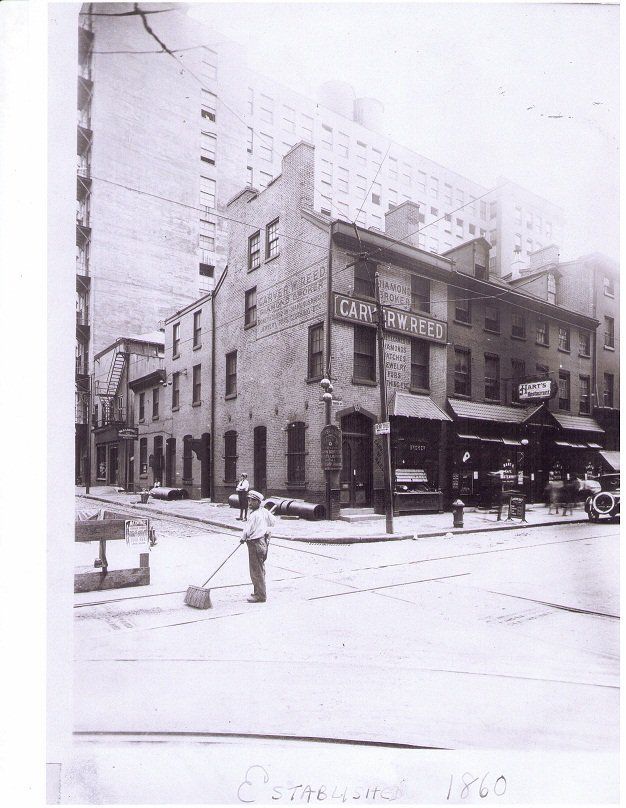 A black and white photo of a city street with a building that says ee on it