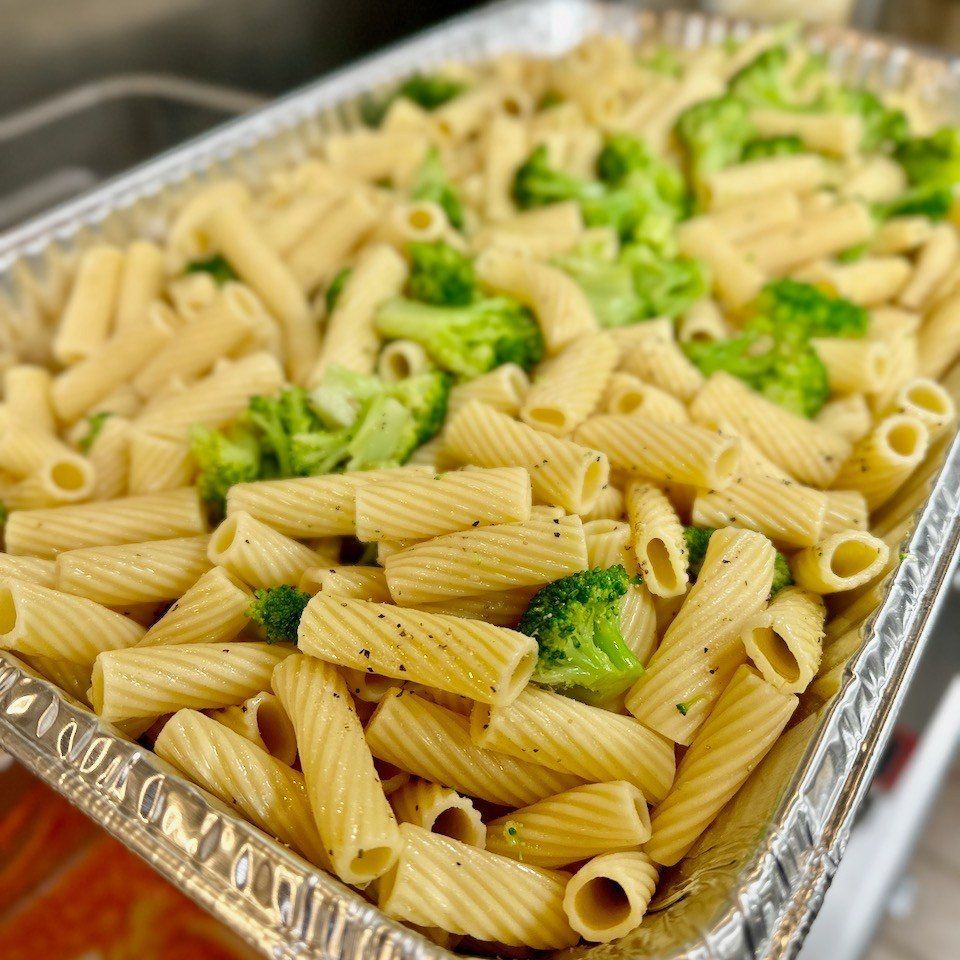 a tray of pasta and broccoli is sitting on a table .