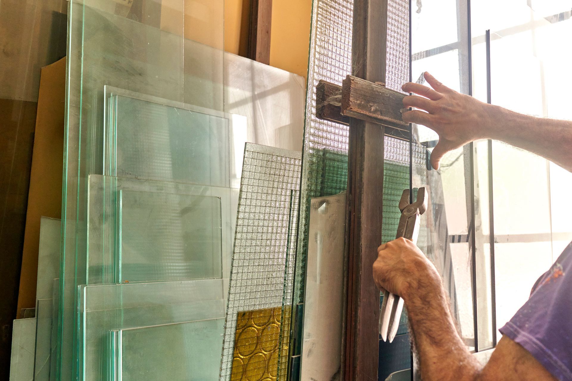 The hands of a local glazier working with glass.