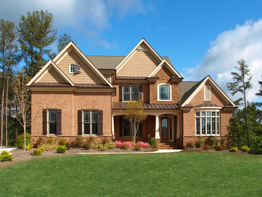 A large brick house with a large lawn in front of it