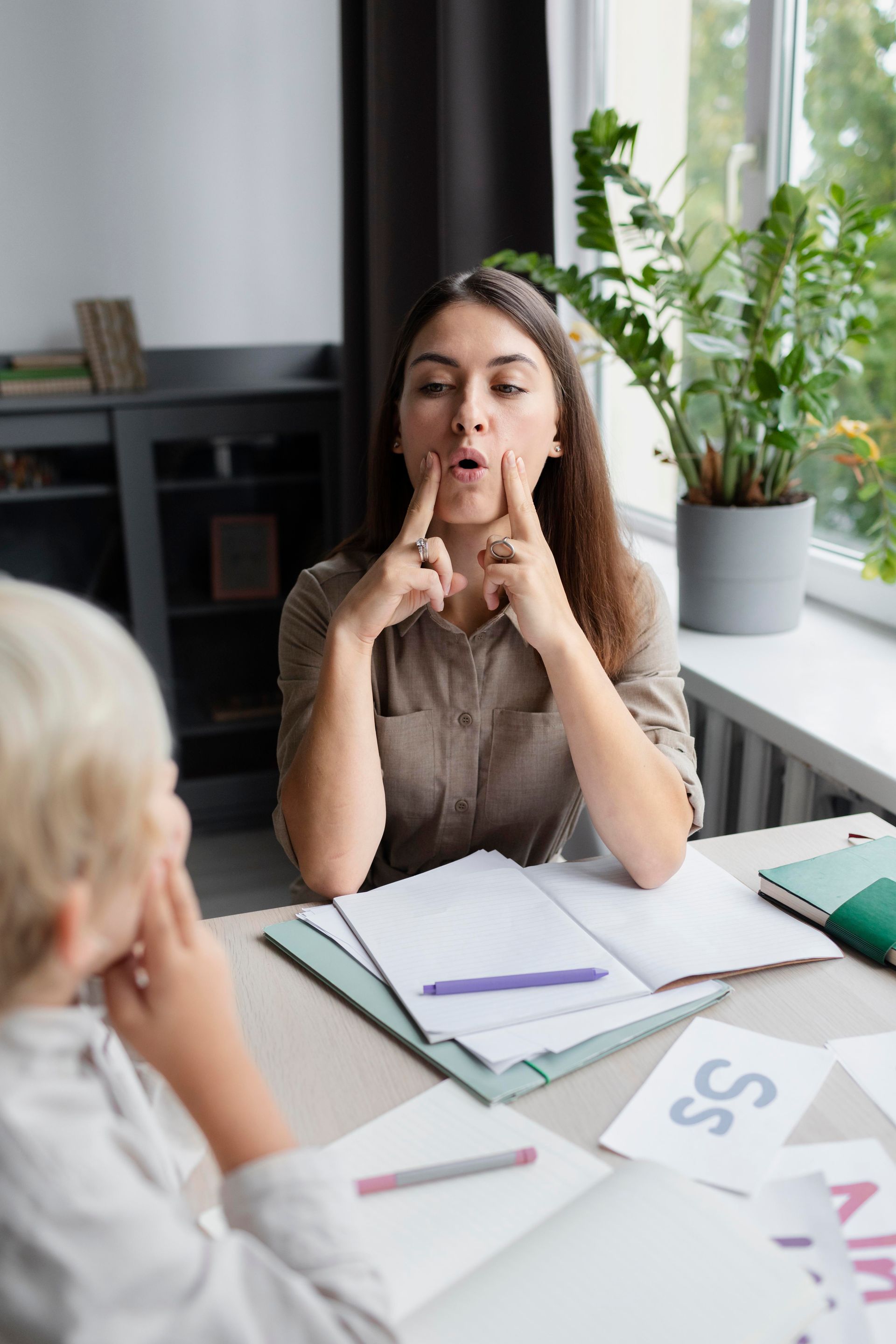 A woman is sitting at a table talking to a boy.