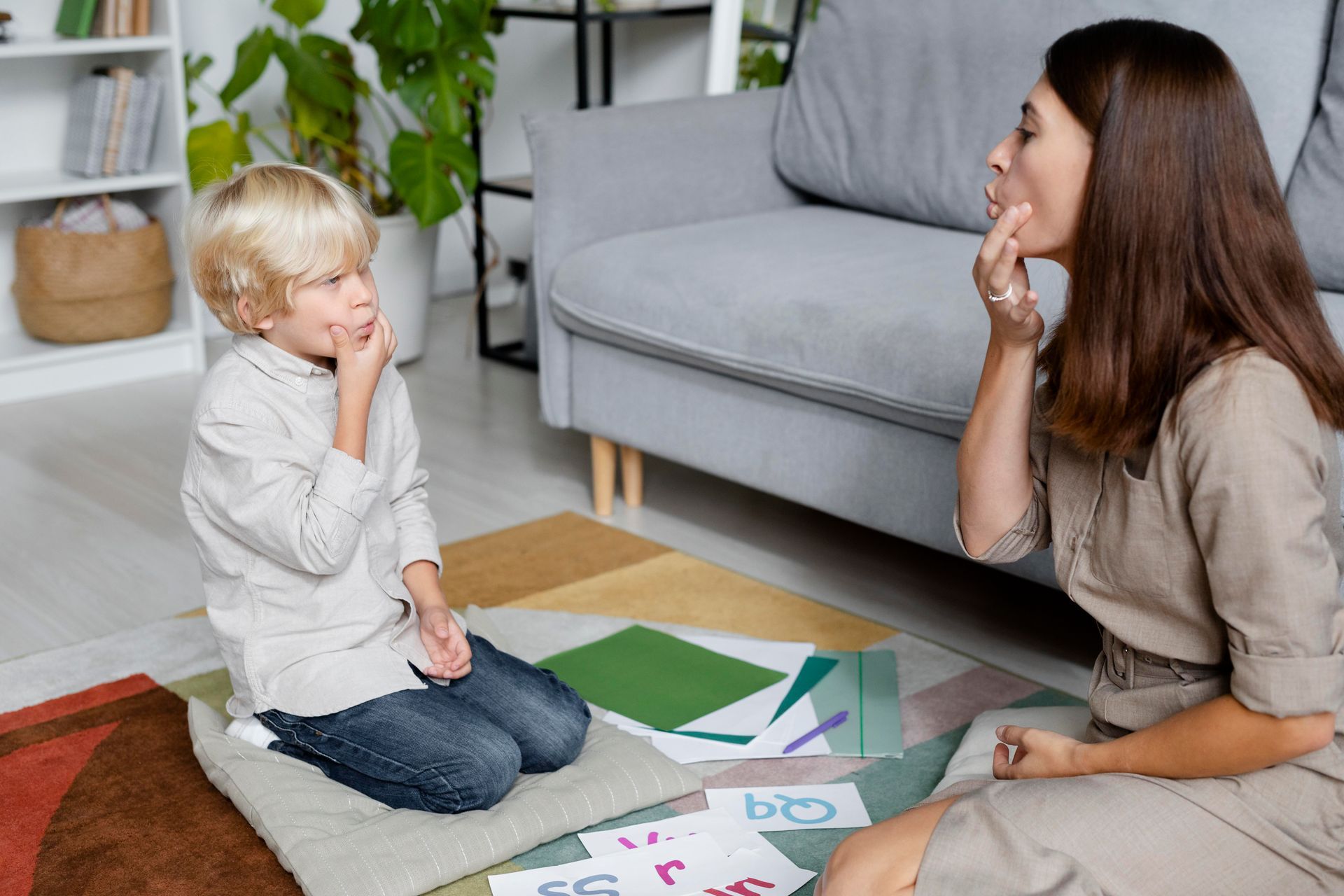 A woman is sitting on the floor talking to a child.