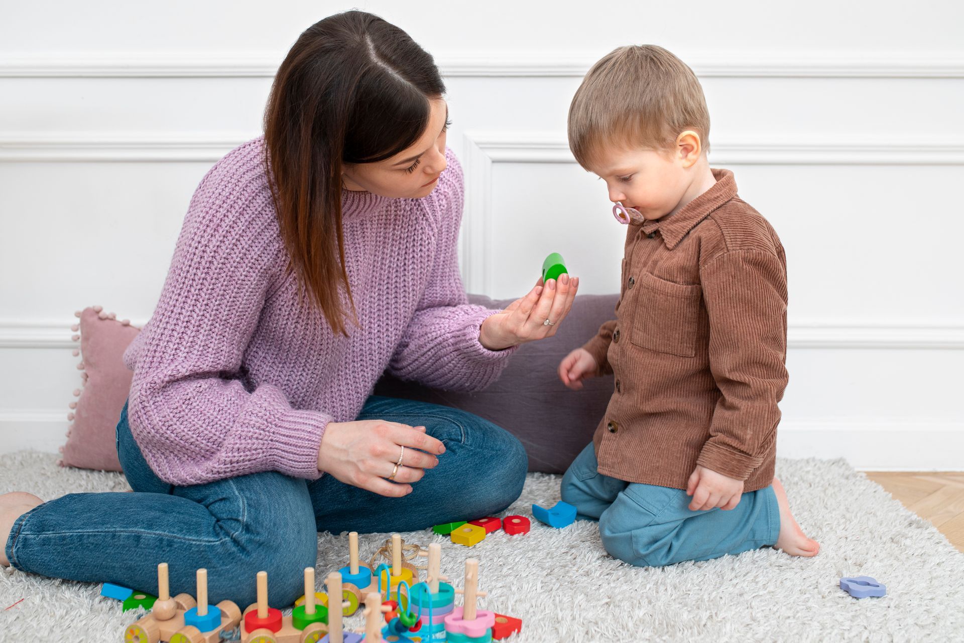 A woman is sitting on the floor playing with a child.