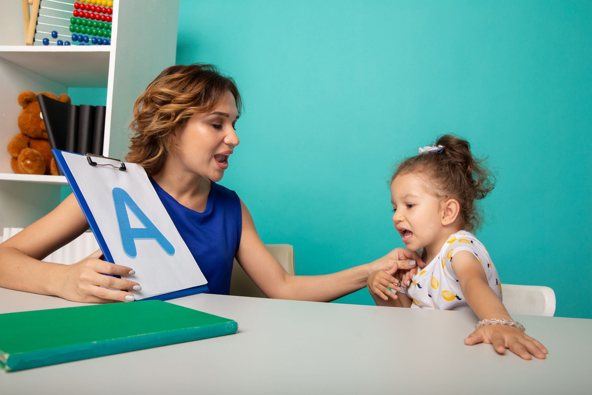 A woman is teaching a little girl how to read the alphabet.