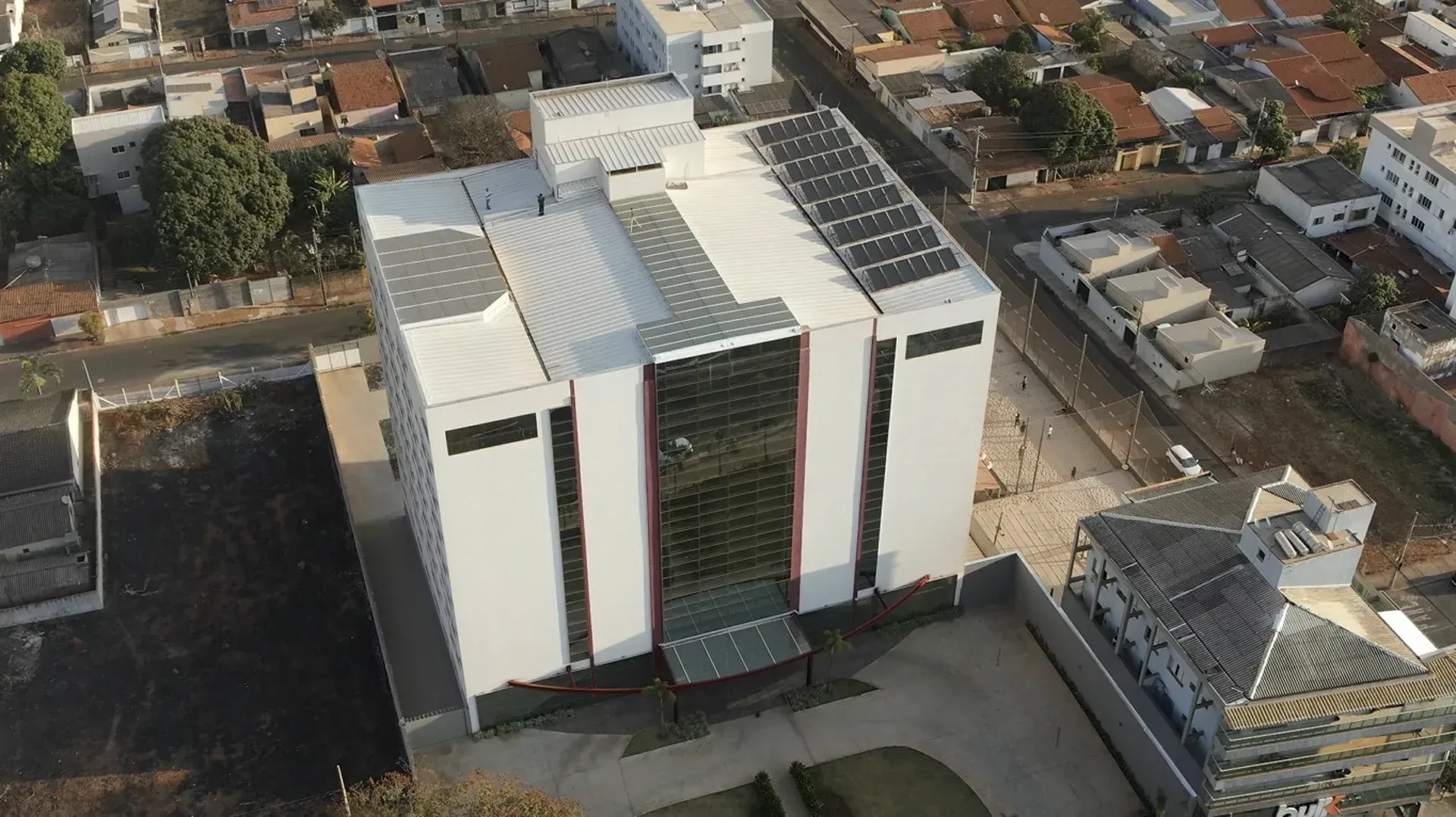 Vista aérea de um edifício moderno branco com painéis solares no telhado.