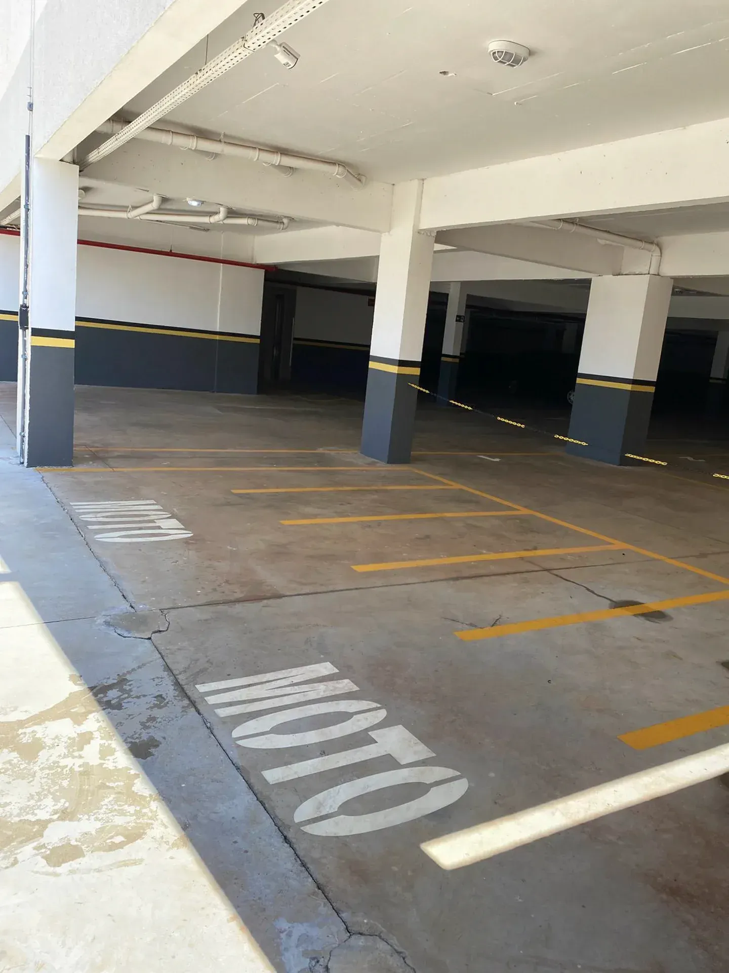 Garagem de estacionamento vazia e bem iluminada, com linhas de estacionamento pintadas e a inscrição