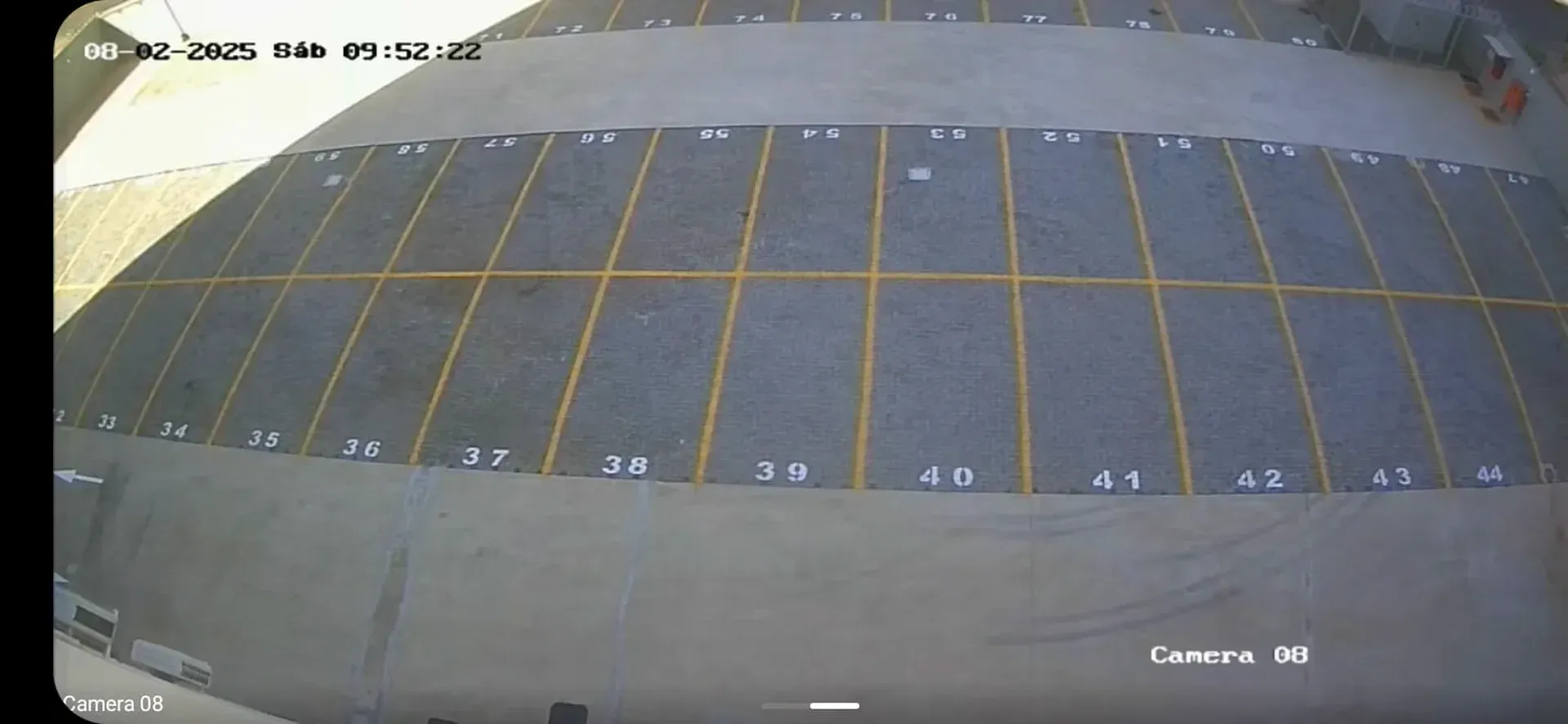 Vista aérea de um estacionamento dividido em vagas numeradas por linhas amarelas.