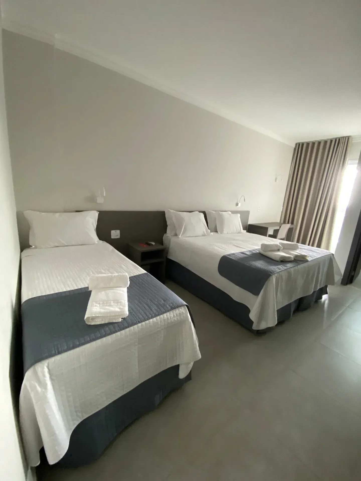 Duas camas em um quarto de hotel com roupa de cama branca e azul.