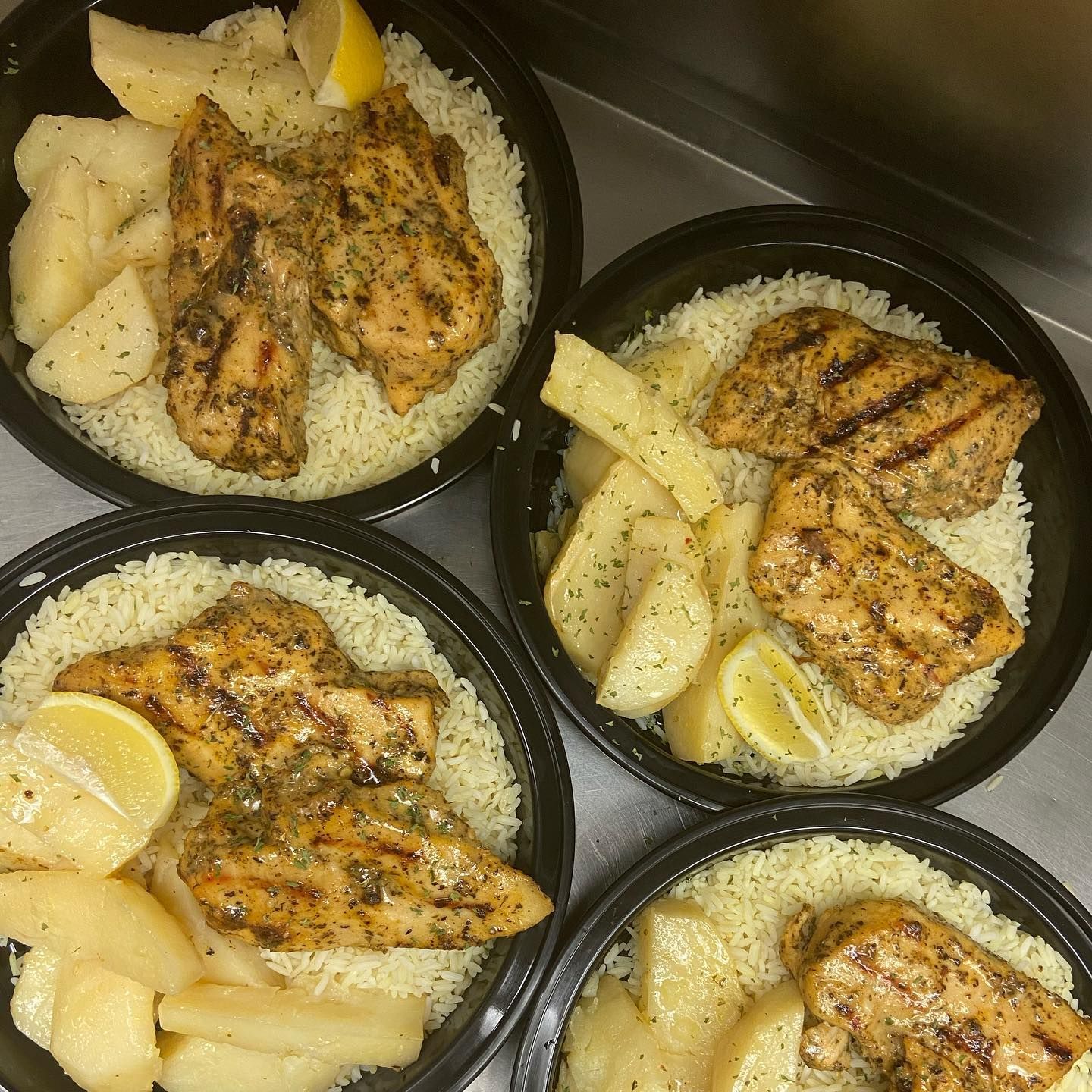 Four bowls of food with rice chicken and potatoes