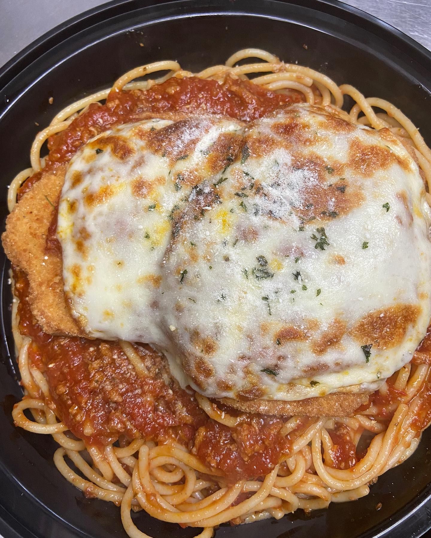 A plate of spaghetti with meatballs and cheese on top.
