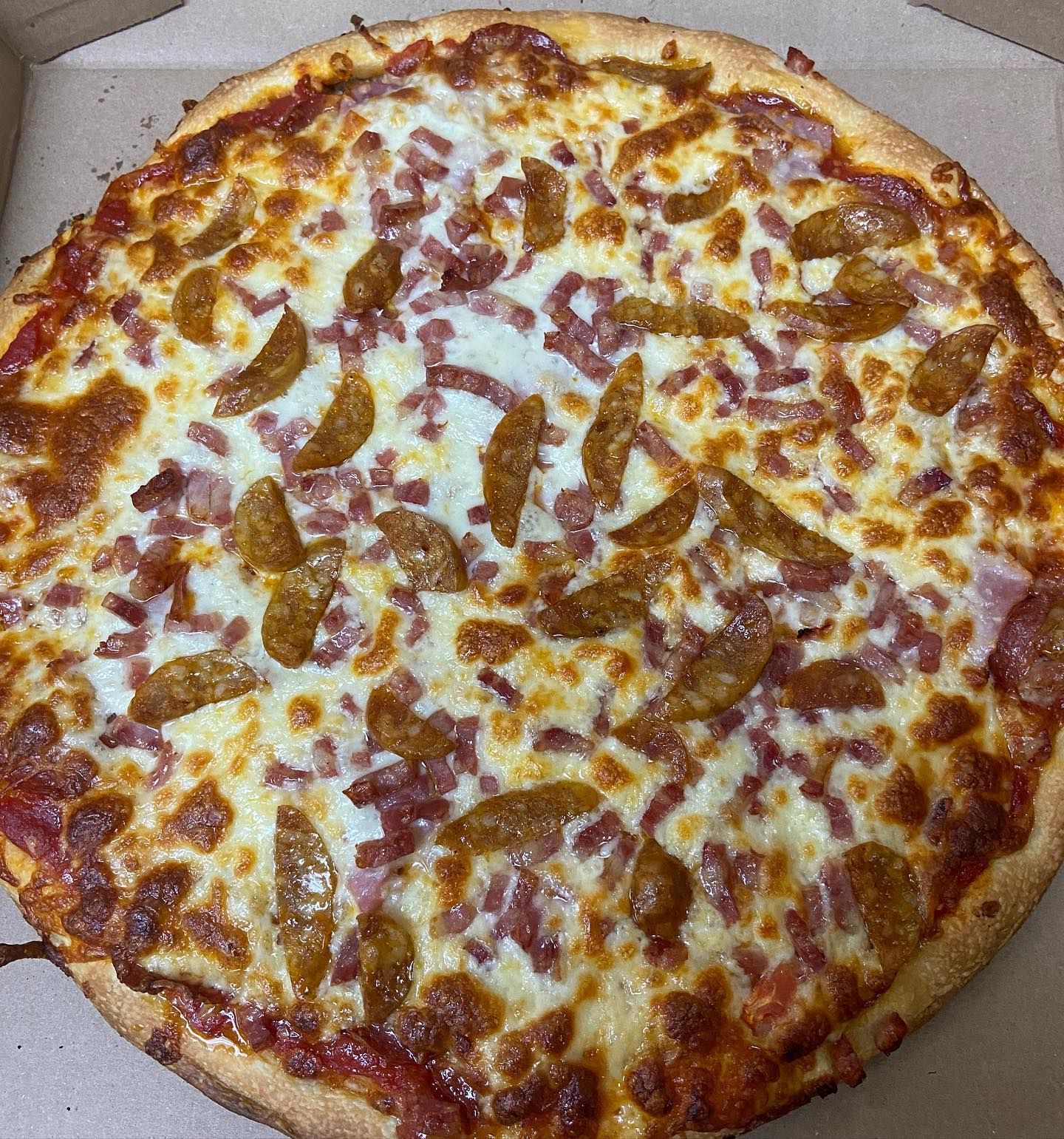 A pizza with a lot of toppings on it is in a box.