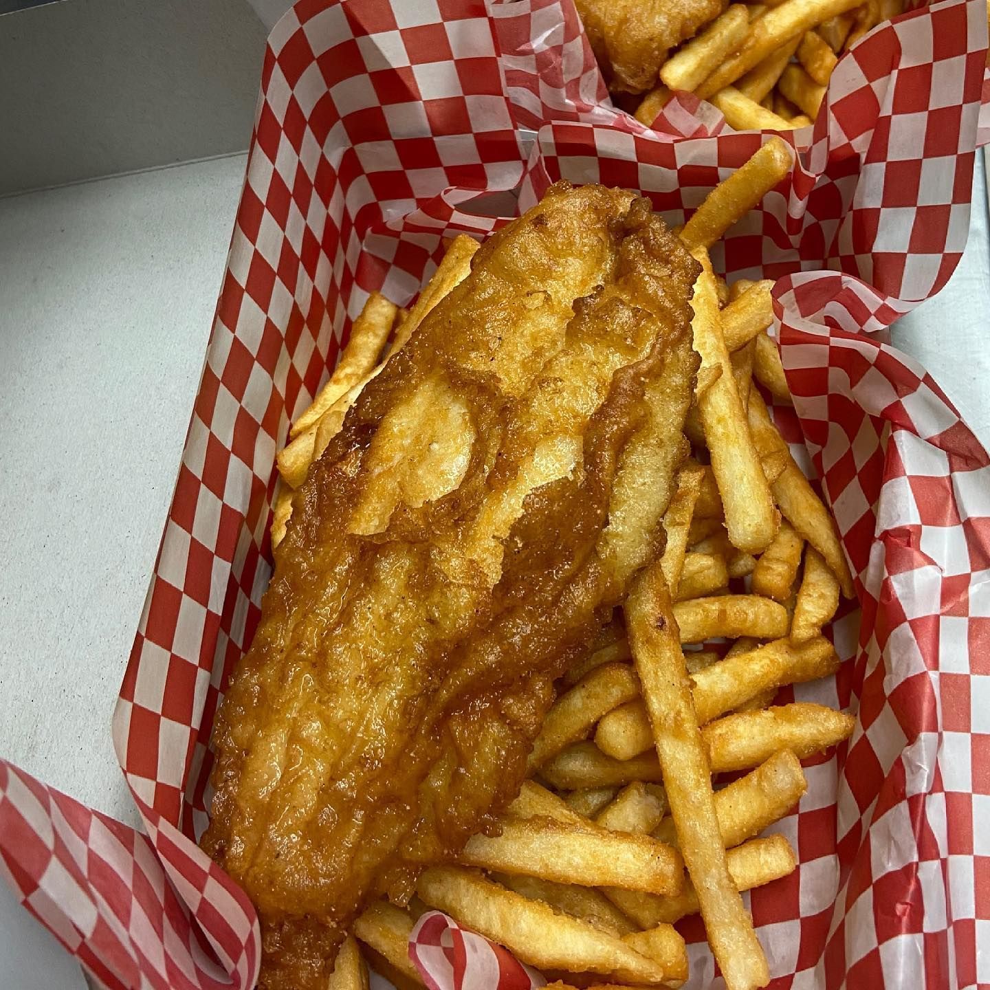 A close up of a fish and french fries in a basket