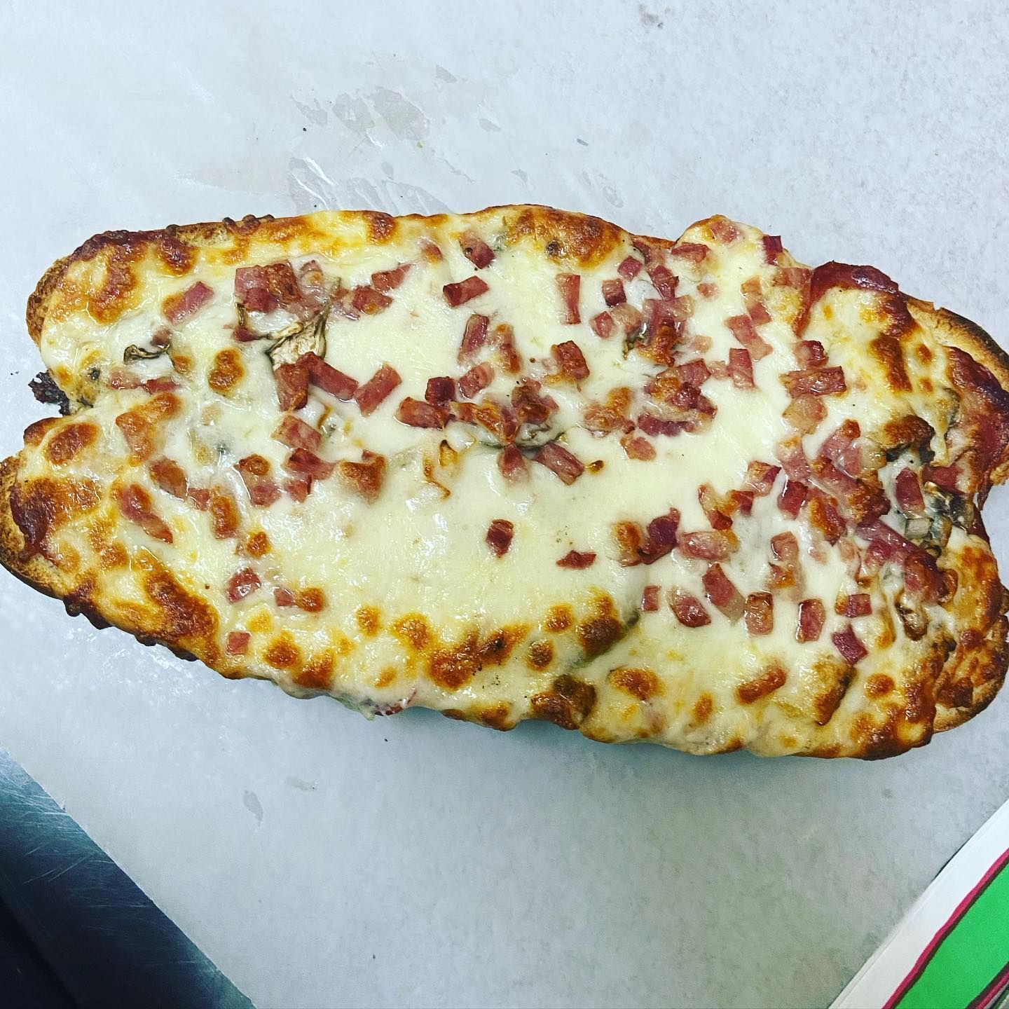 A pizza with cheese and bacon on it is sitting on a table.