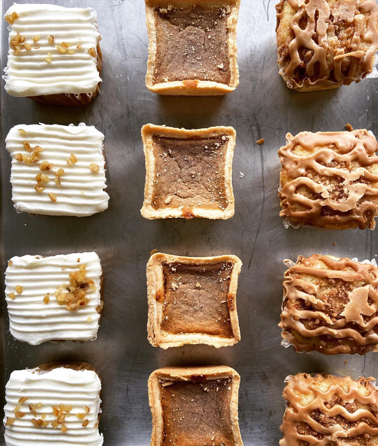 A variety of desserts are lined up on a metal tray