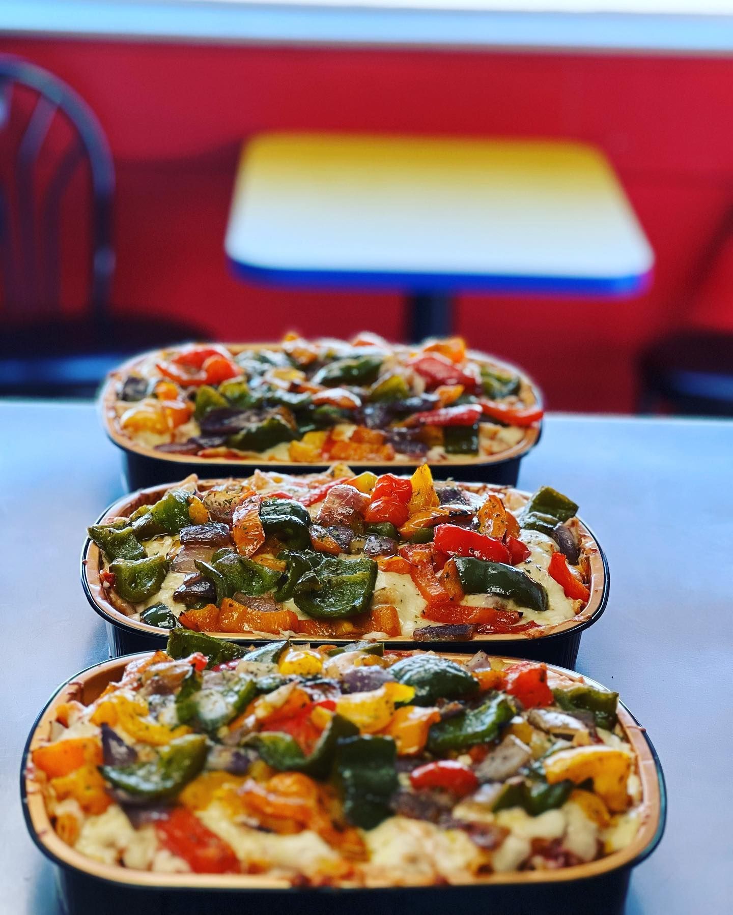 Three casserole dishes filled with vegetables are lined up on a table