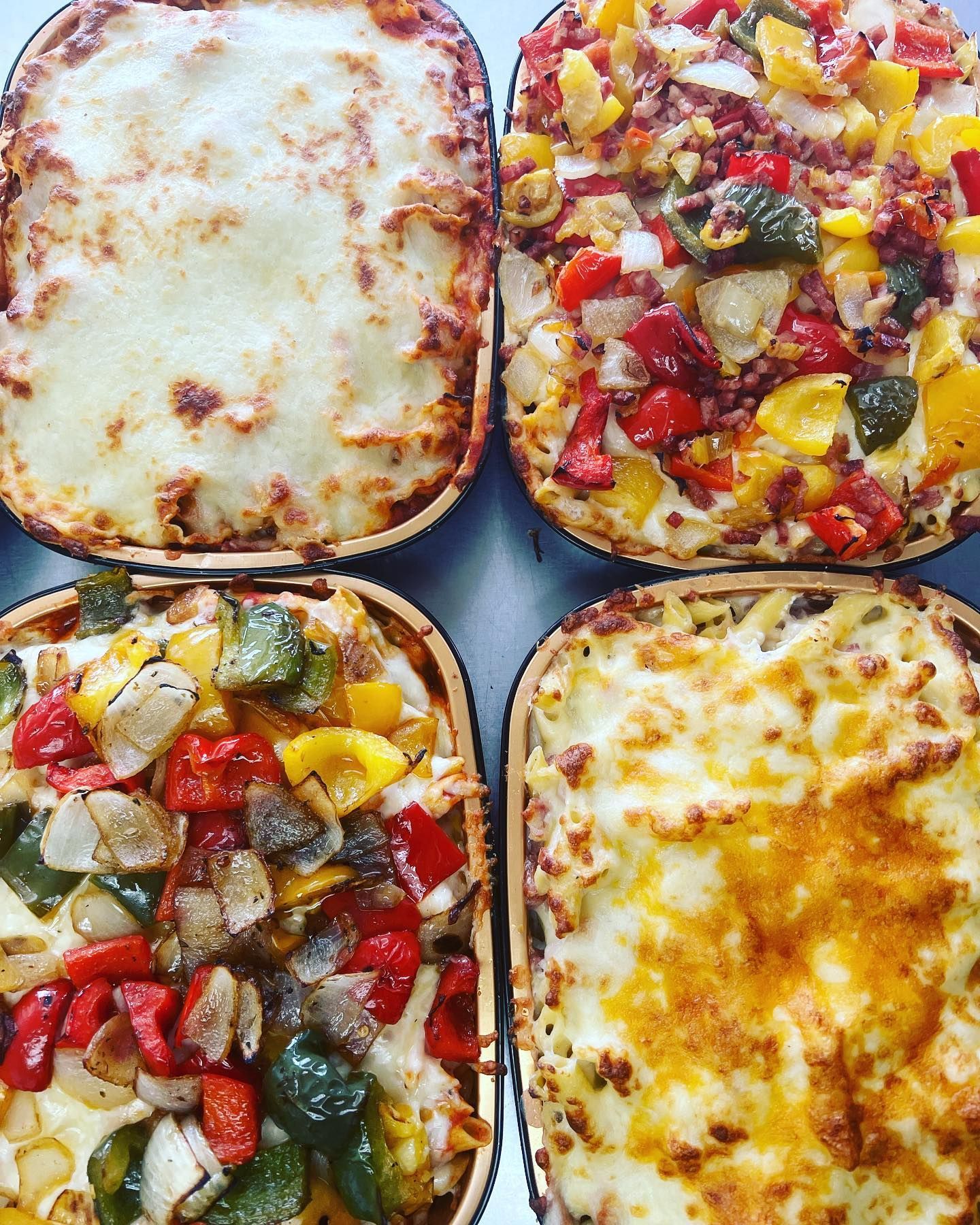Four pizzas with different toppings are sitting on a table.
