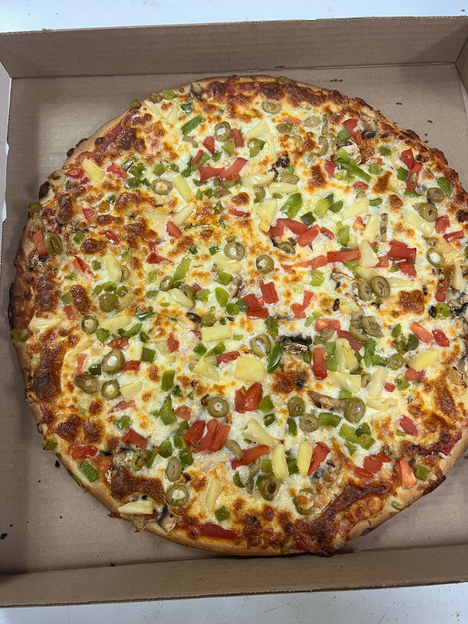 A pizza with a lot of toppings is in a box.