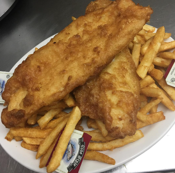 A white plate topped with fried fish and french fries