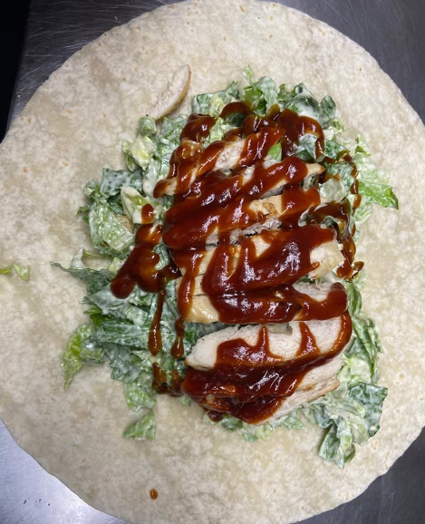 A tortilla with chicken lettuce and barbecue sauce on top