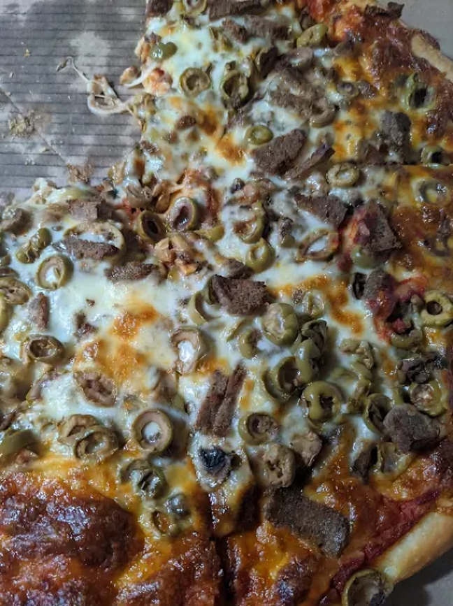 A pizza with tomatoes , cheese and basil on a wooden cutting board.