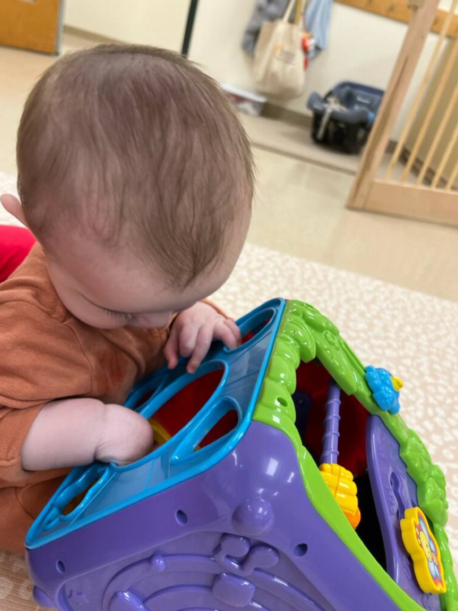 A baby is playing with a toy on the floor