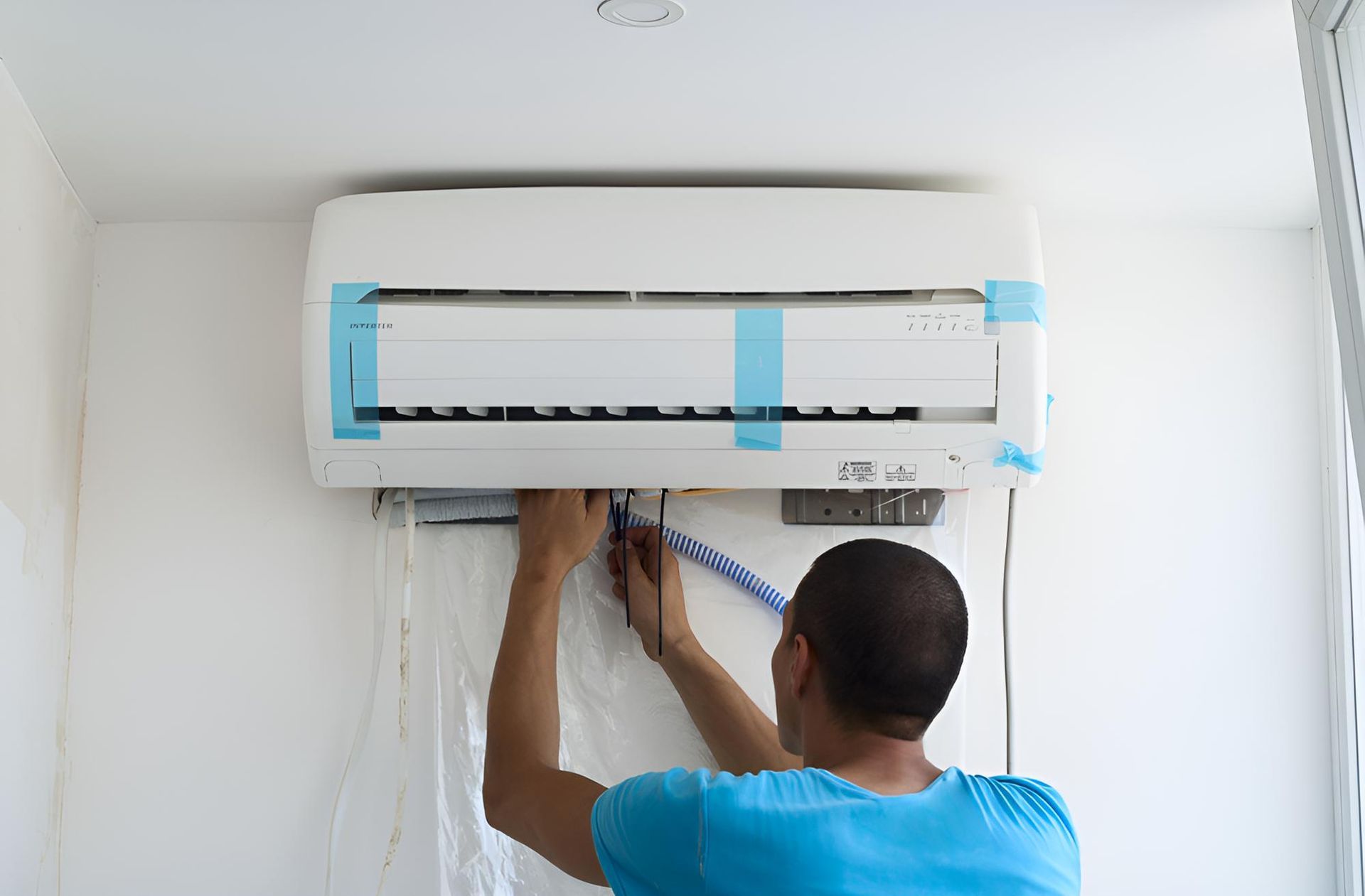 Man is Installing an Air Conditioner on a Wall — Tec Electrical & Air In Sandgate, QLD