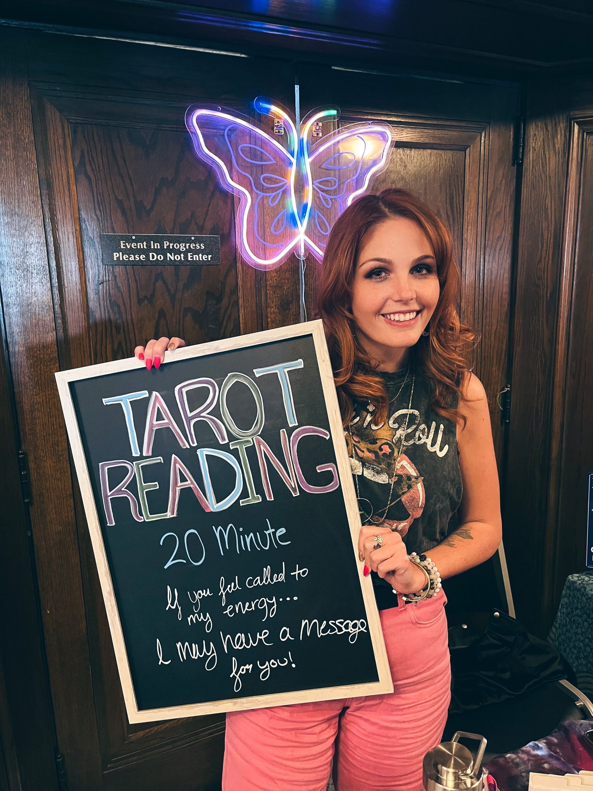 A woman is holding a chalkboard that says `` tarot reading ''.