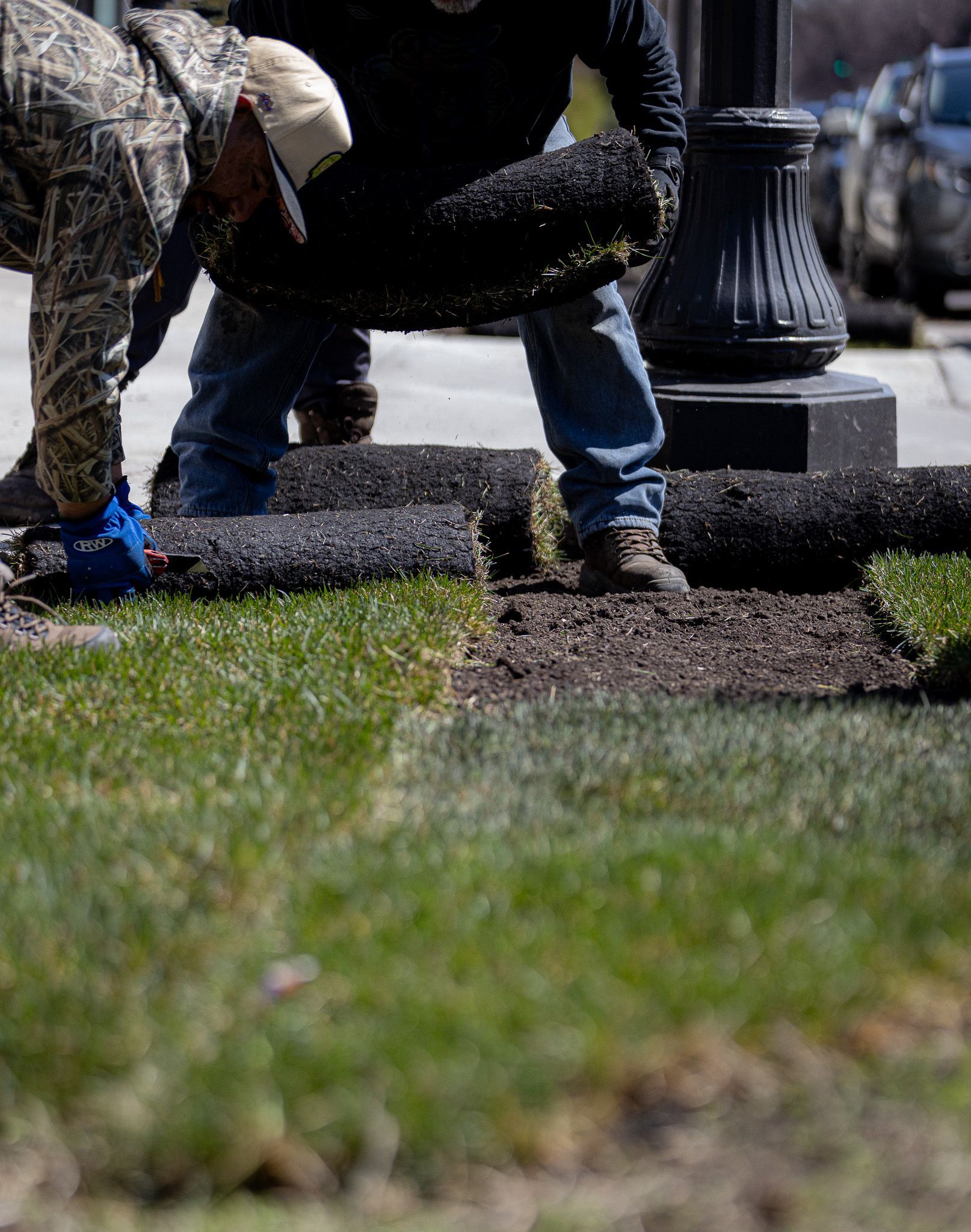 A man is laying a roll of grass on the ground.
