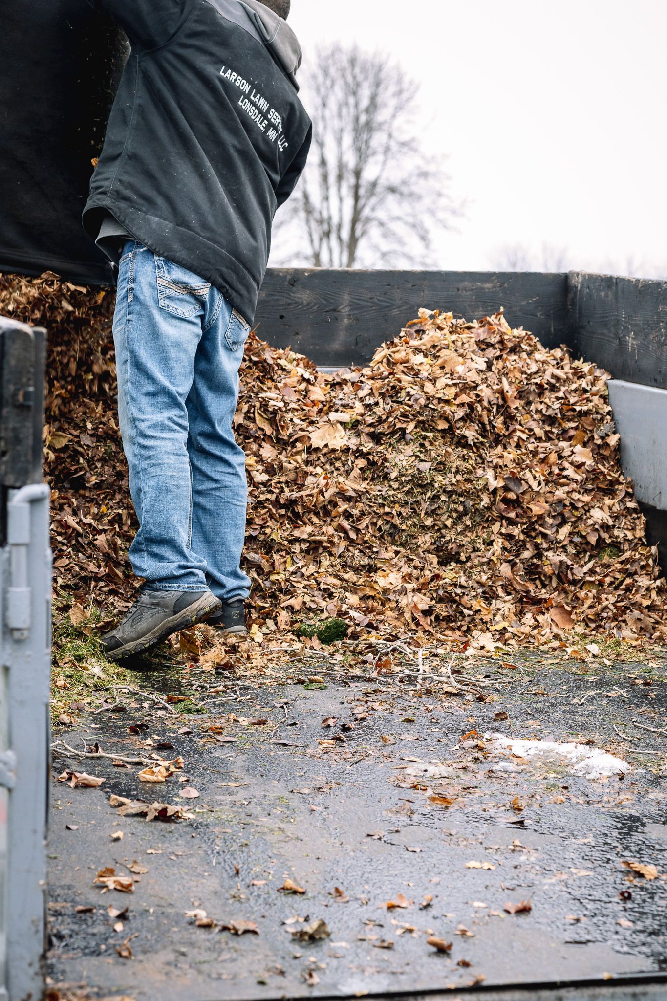 A man is standing in front of a pile of leaves.