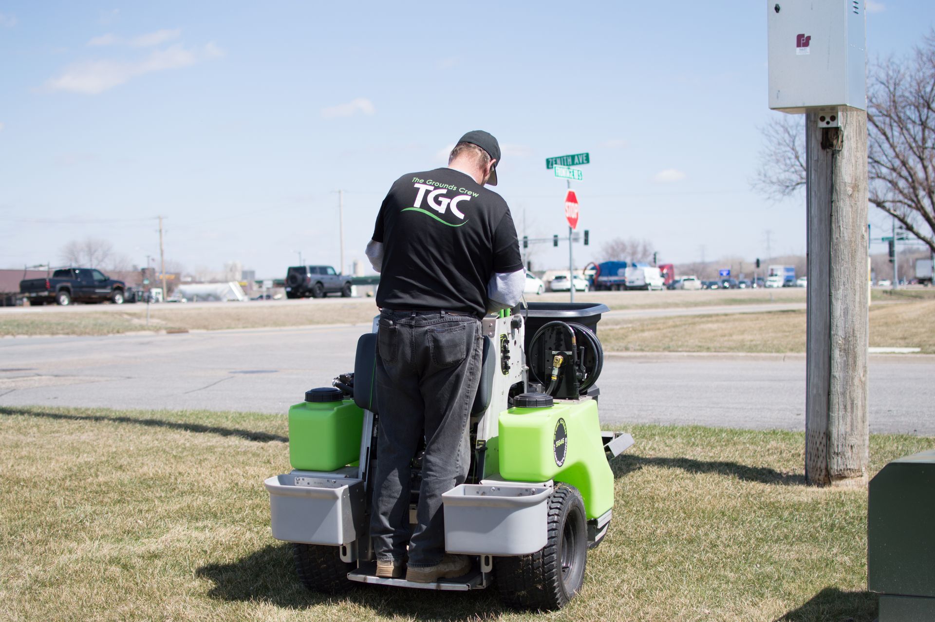 A man is riding a green lawn mower in a grassy field.