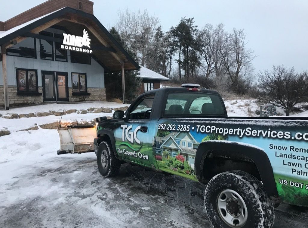A TGC truck is parked in the snow in front of a building