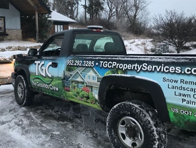 A tgc property services truck is parked in the snow in front of a house.