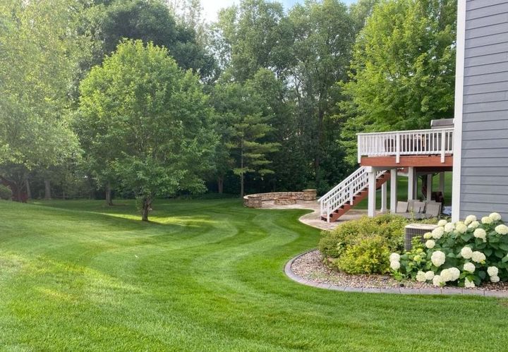 A house with a large lawn and a deck in the backyard.