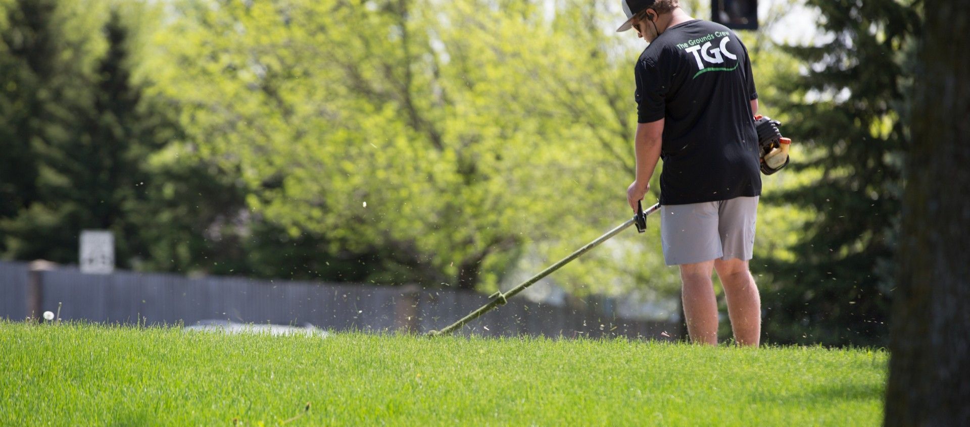 A man is mowing a lush green lawn with a lawn mower.