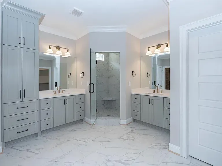 White kitchen cabinets with gold handles, black countertop, and diamond-patterned backsplash.