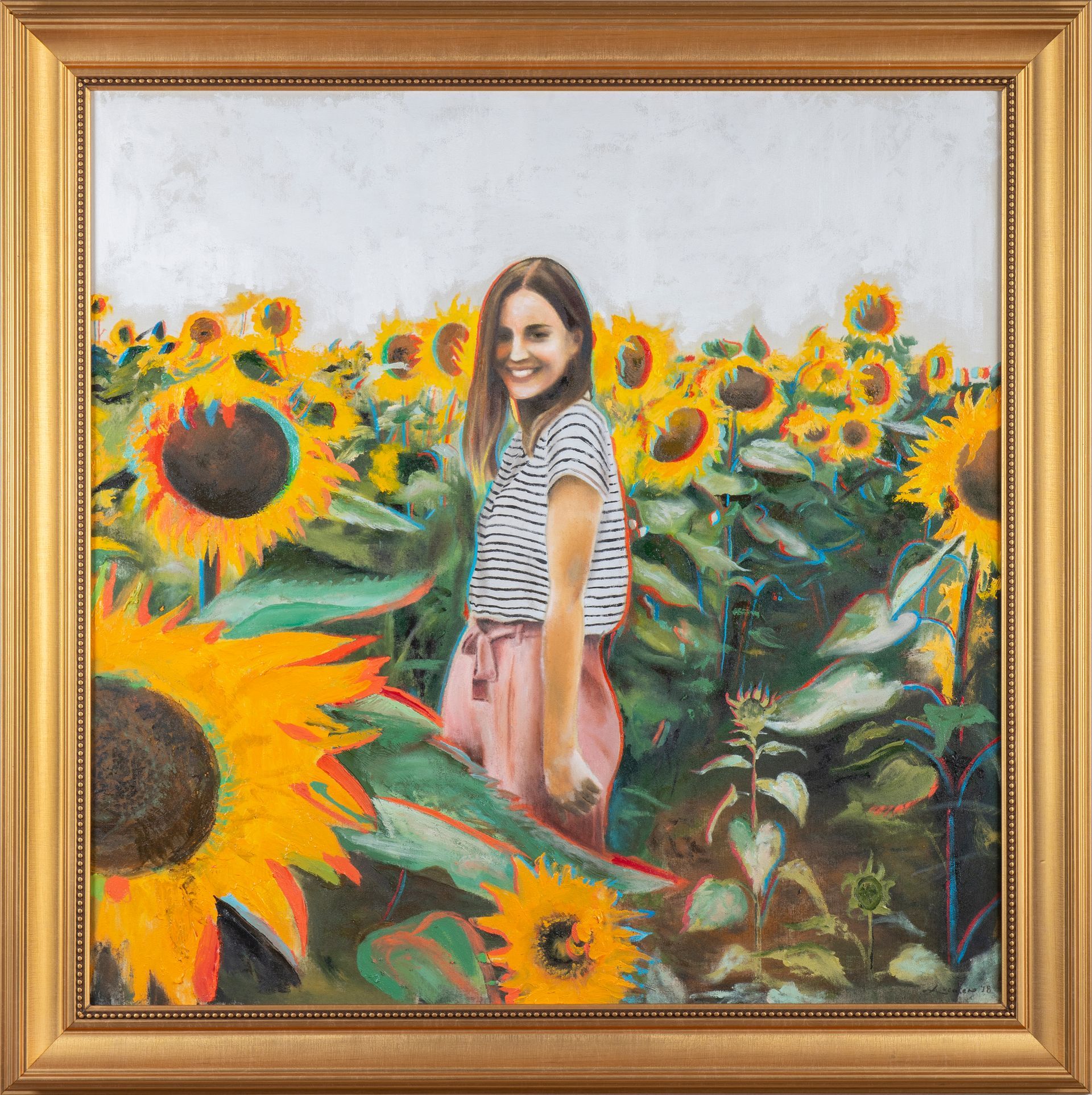 Mujer sonriendo en un campo de girasoles, vestida con camisa de rayas y pantalones rosas.