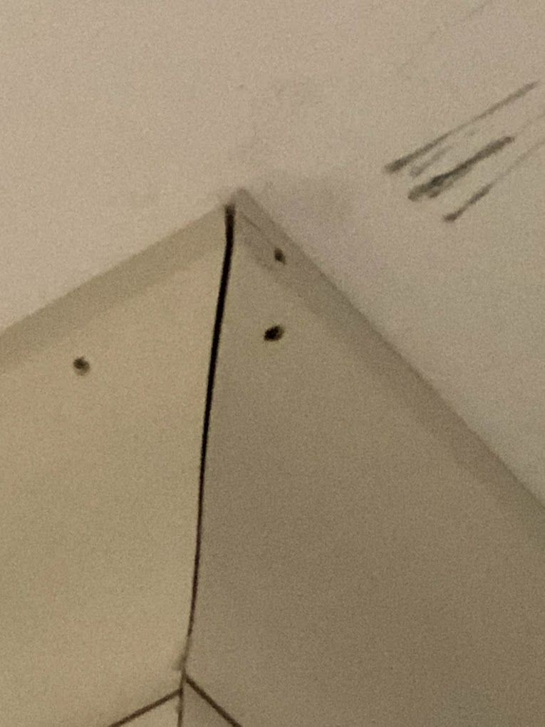 A close up of a corner of a wall with a hole in it