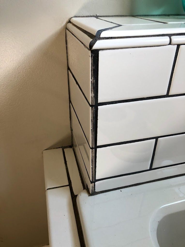 A bathroom counter with white tiles and a sink