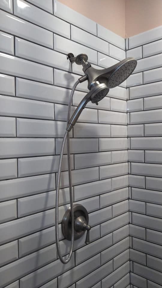 A shower head is hanging on a white brick wall