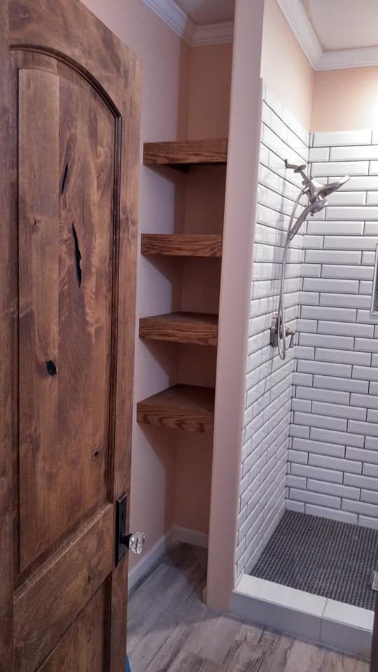 A bathroom with a wooden door and a walk in shower