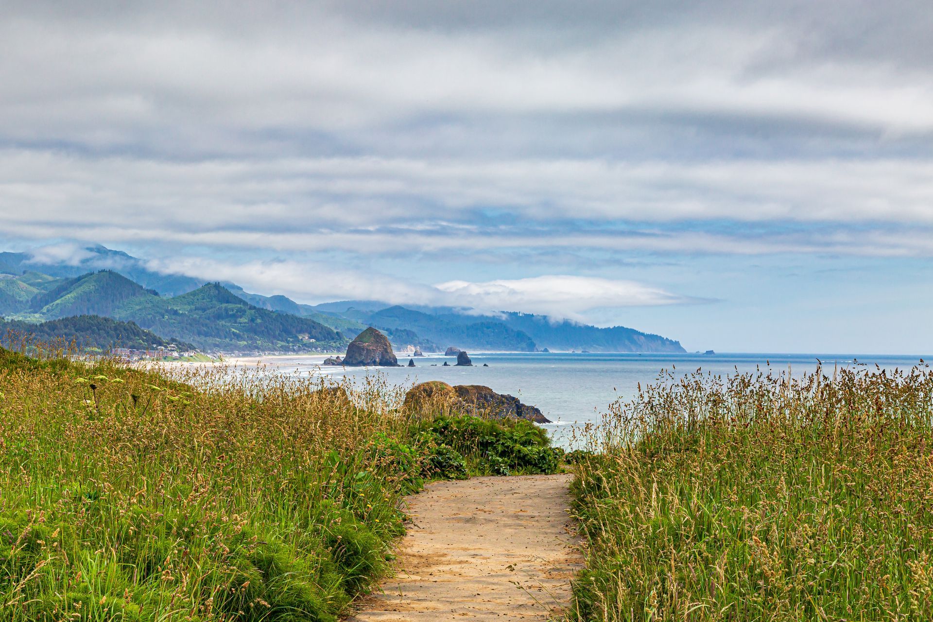 A path leading to the ocean with mountains in the background.
