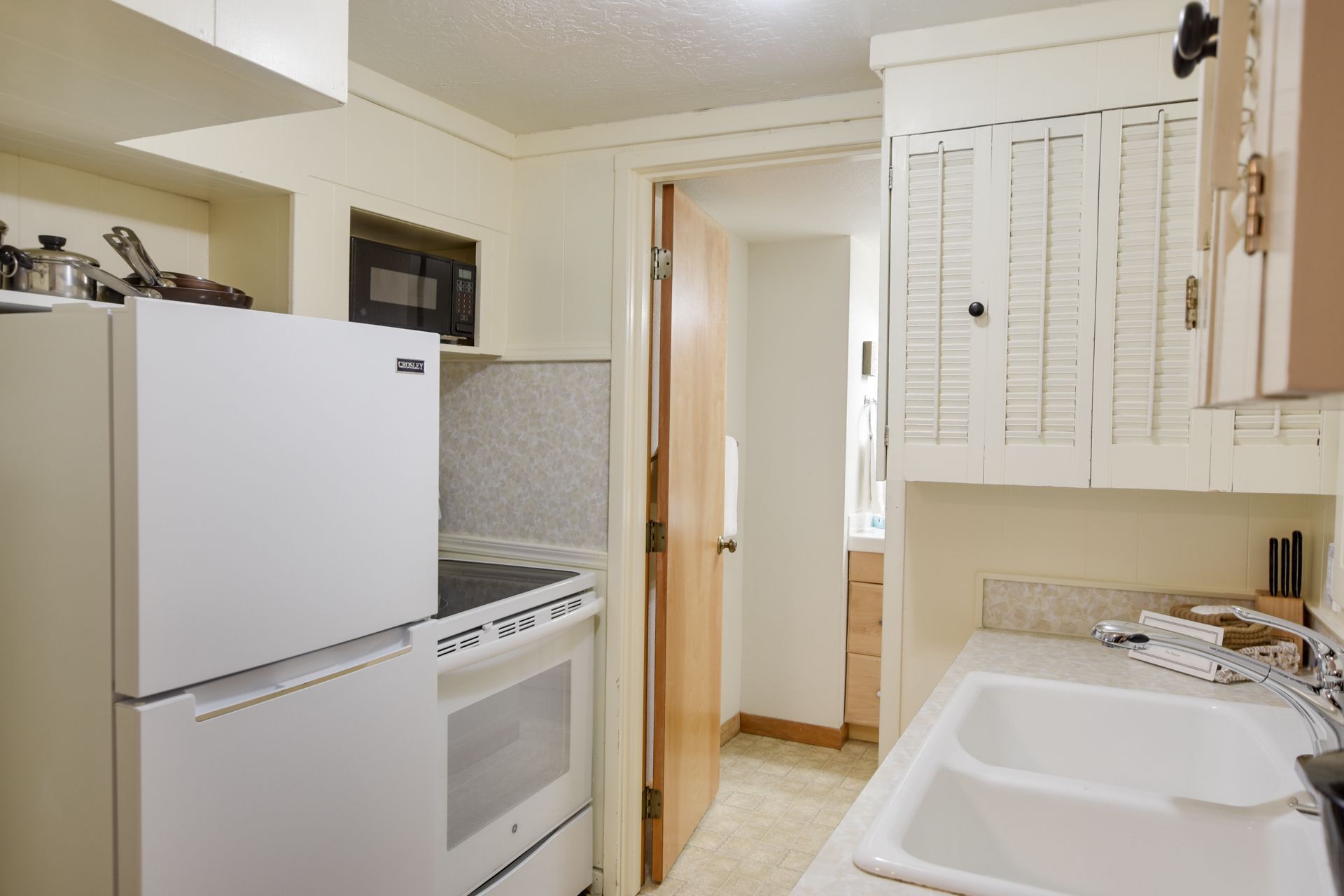 A kitchen with a white refrigerator stove and sink