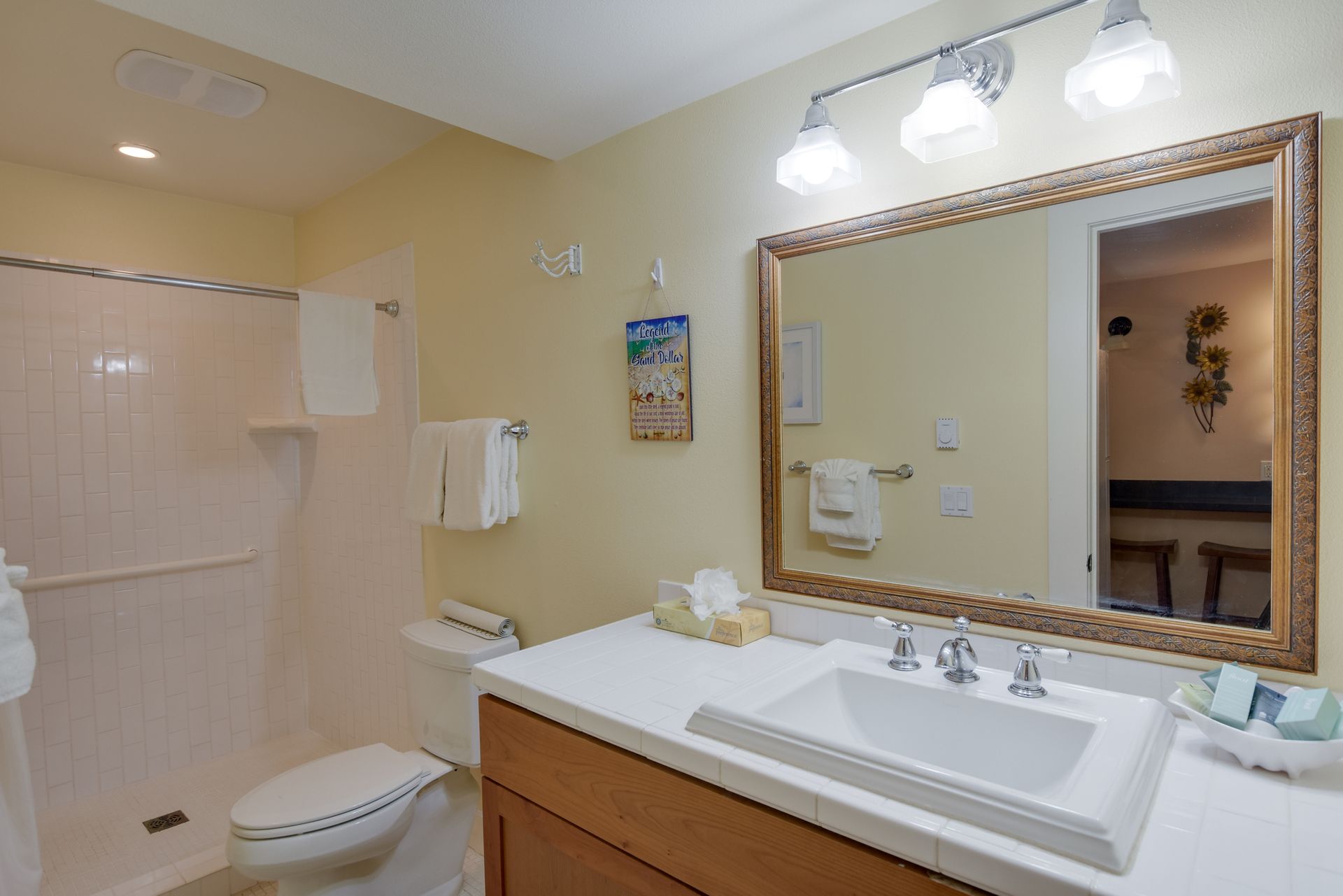 A bathroom with a toilet , sink , mirror and shower.