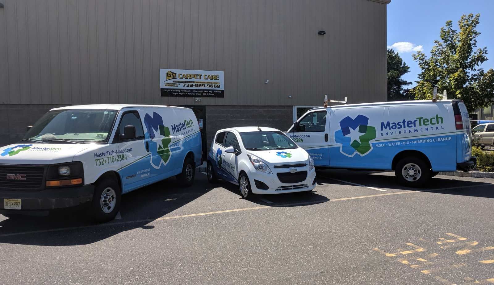 Three Mastertech vans are parked in front of a building