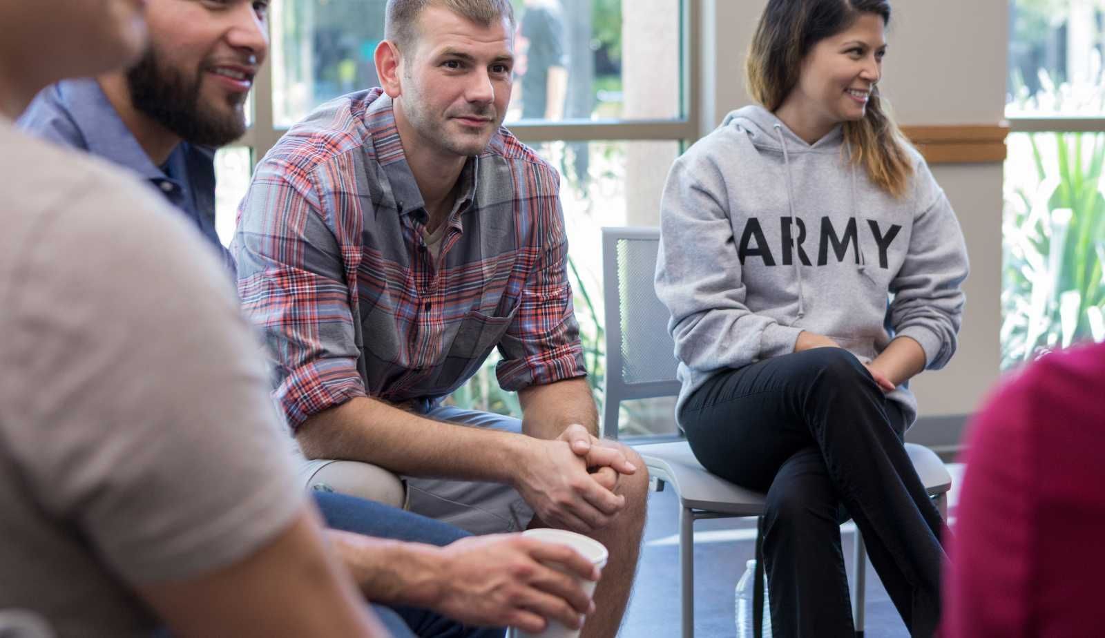 A group of people are sitting in a circle talking to each other.