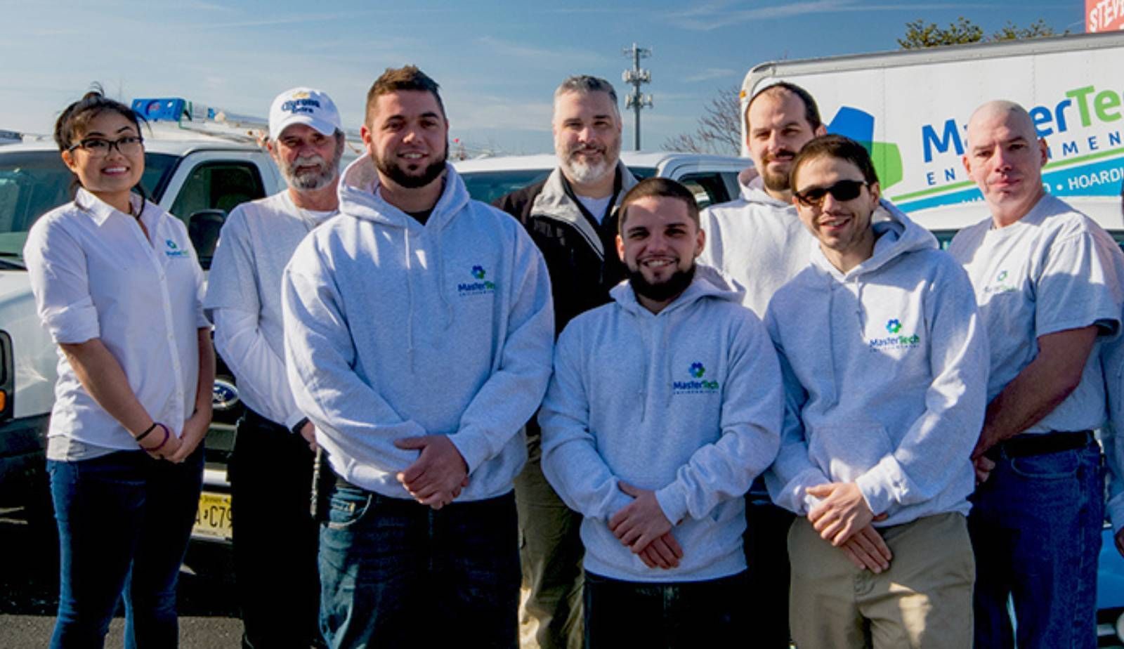 A smiling Mastertech franchise owner standing in front of a branded service van.