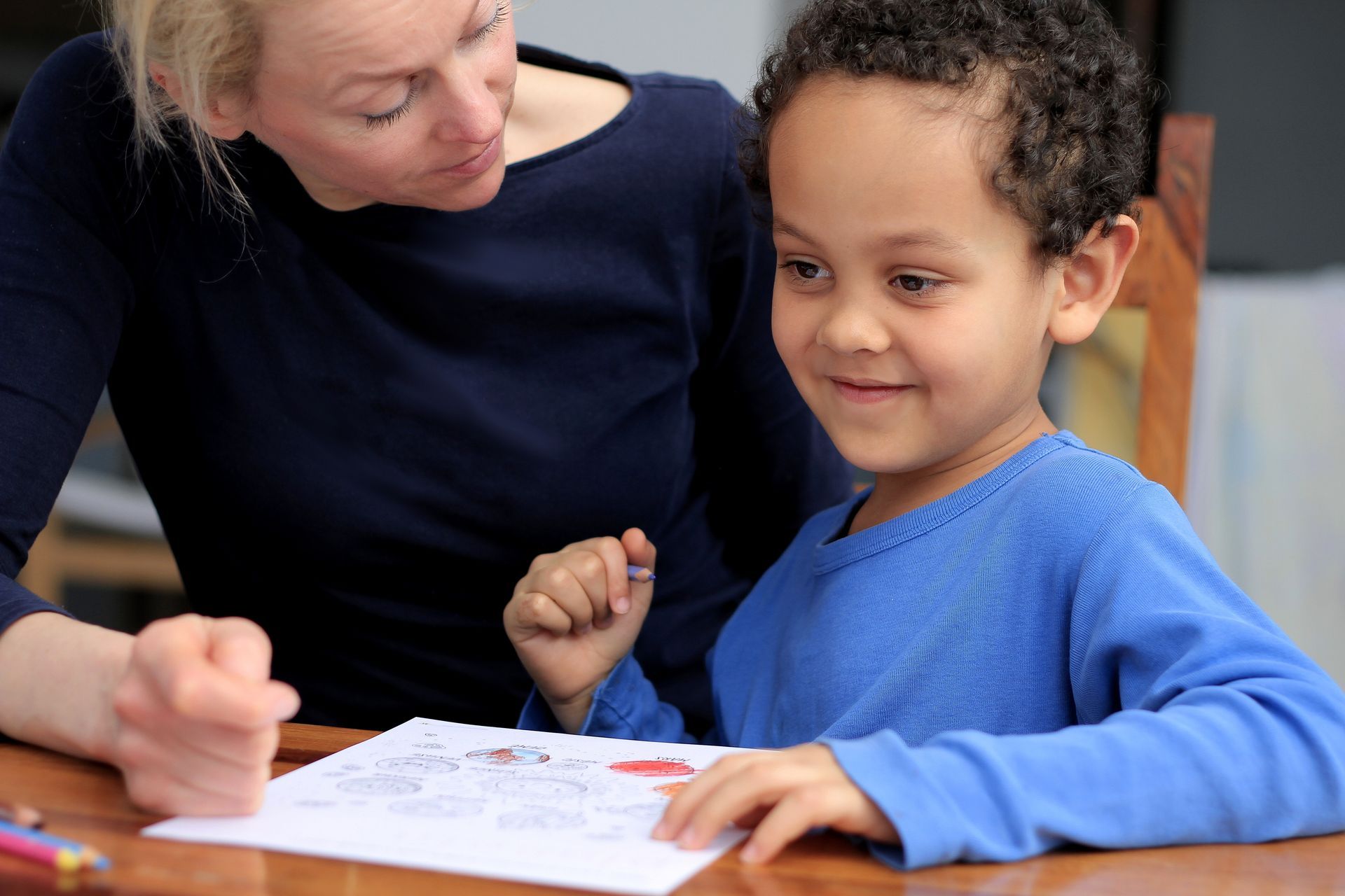 A woman is helping a young boy with his homework.