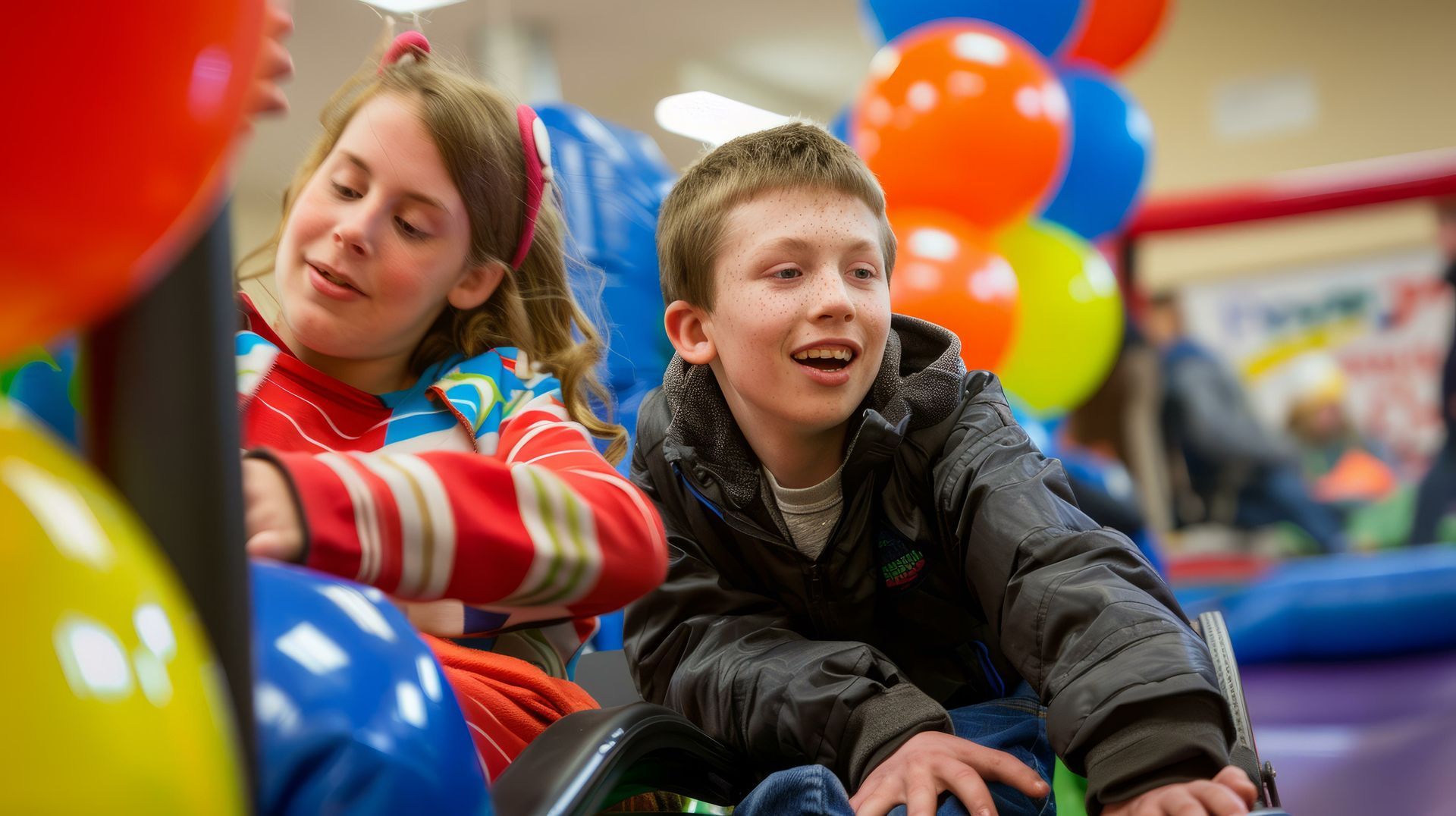 A boy and a girl are playing on a slide with balloons in the background.