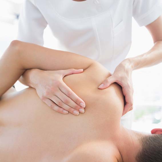 Professional therapist giving shoulder massage to man