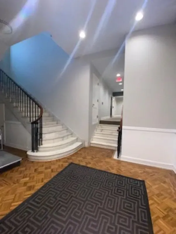 A hallway with stairs and a rug on the floor